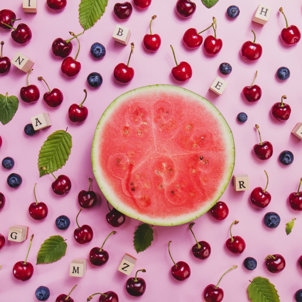 Половина арбуза с ягодами вишни и черники на столе