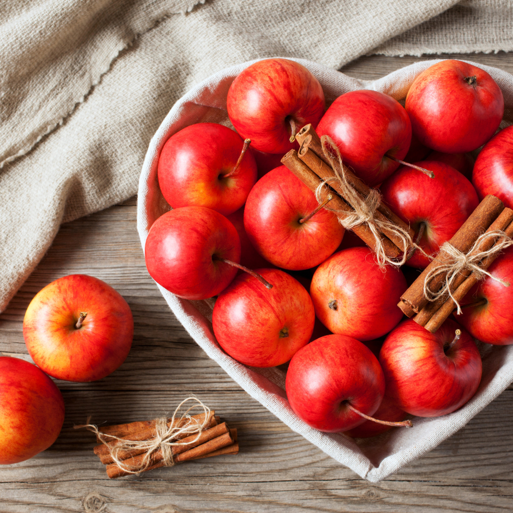 Красные яблоки в тарелке в форме сердца с корицей