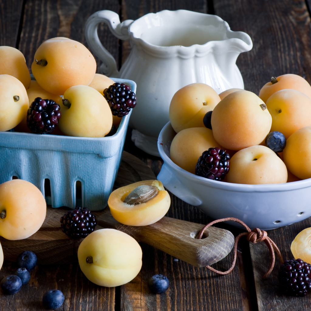 Спелые абрикосы и ягоды на столе 