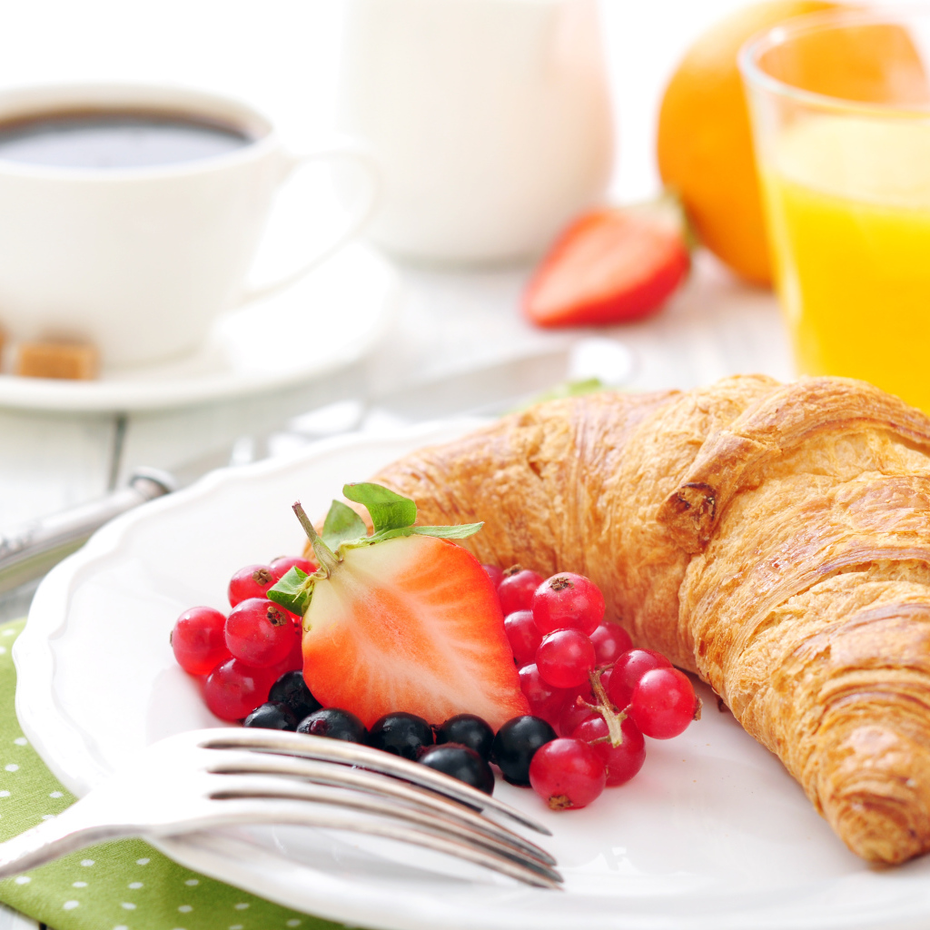 Свежий круассан на белой тарелке с ягодами 