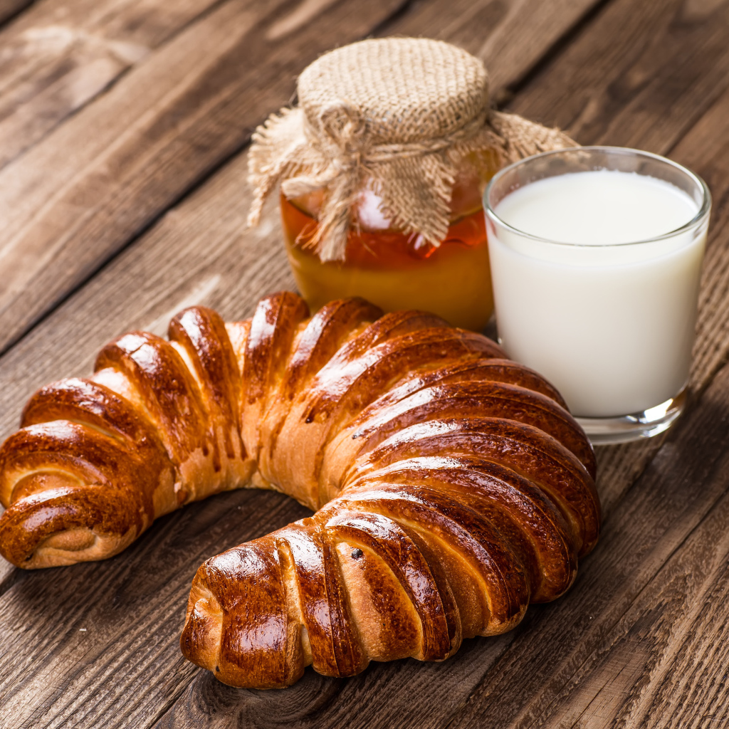 Свежая выпечка на столе с медом и стаканом молока