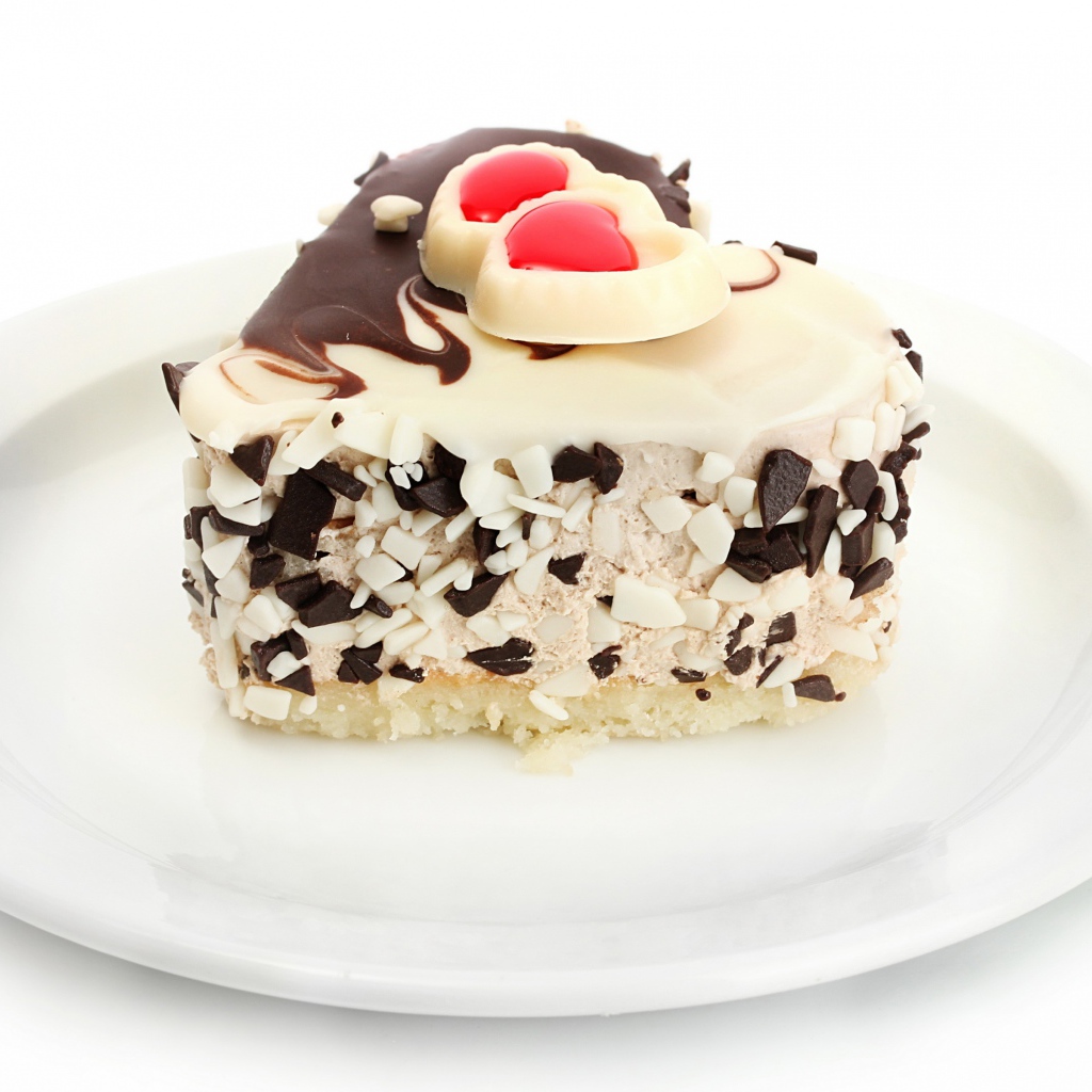 Аппетитное пирожное в форме сердца с шоколадом на белой тарелке