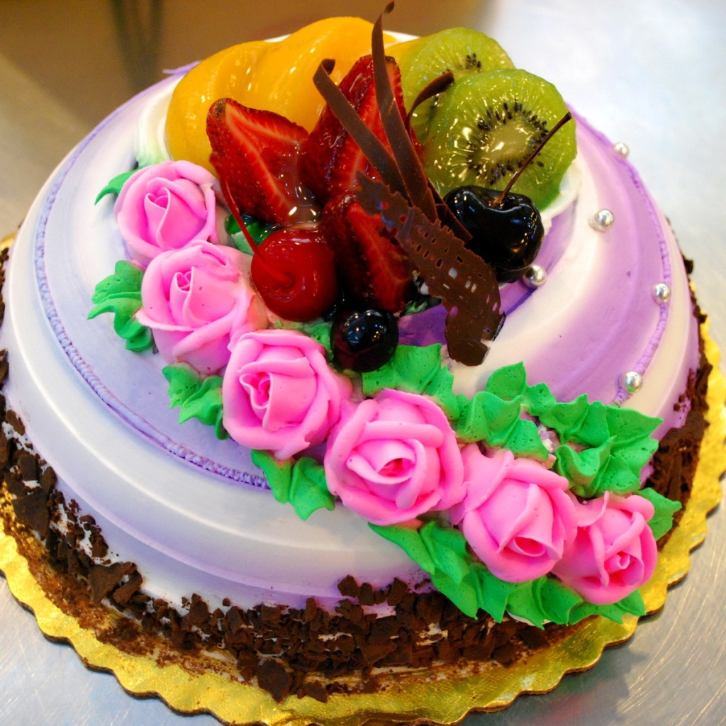 Красивый торт с фруктами украшен розовыми розами из крема