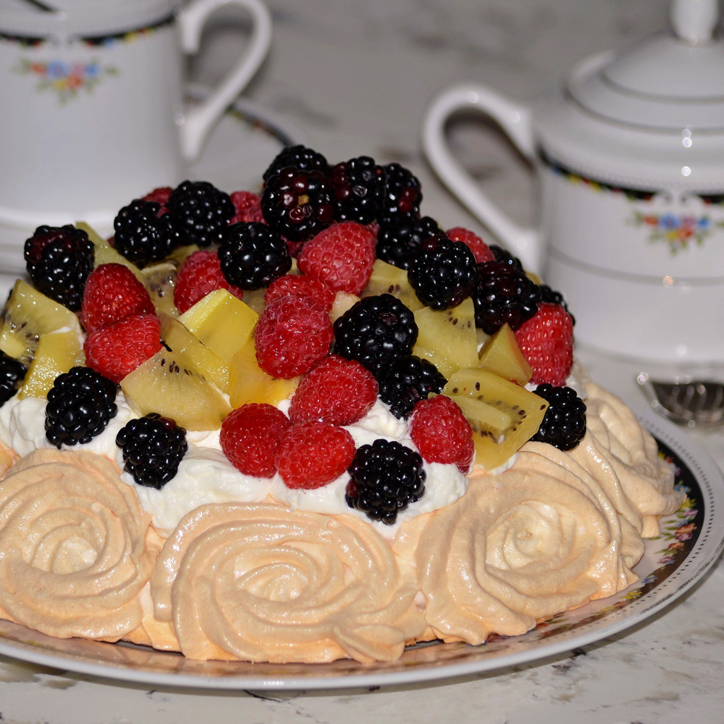 Торт с безе и свежими ягодами на столе 