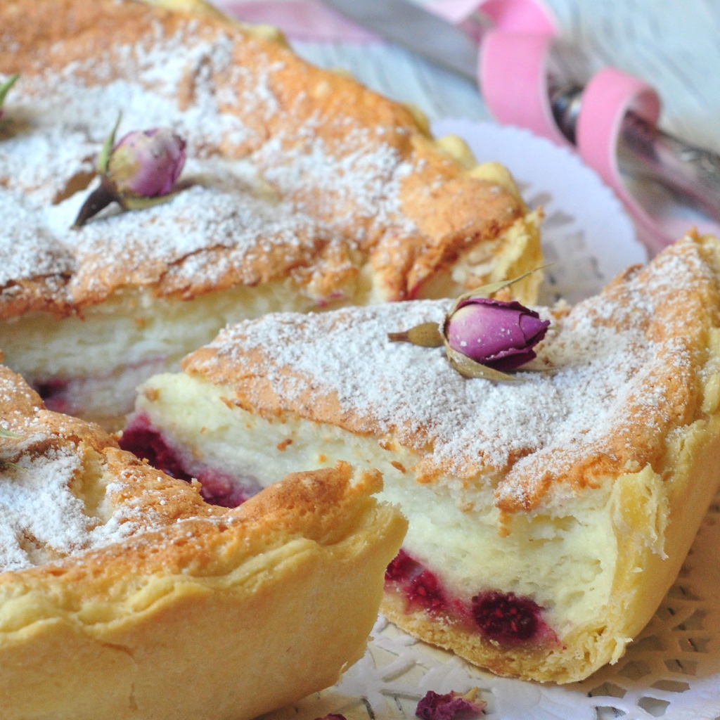 Пирог с суфле и малиной посыпанный сахарной пудрой и цветами