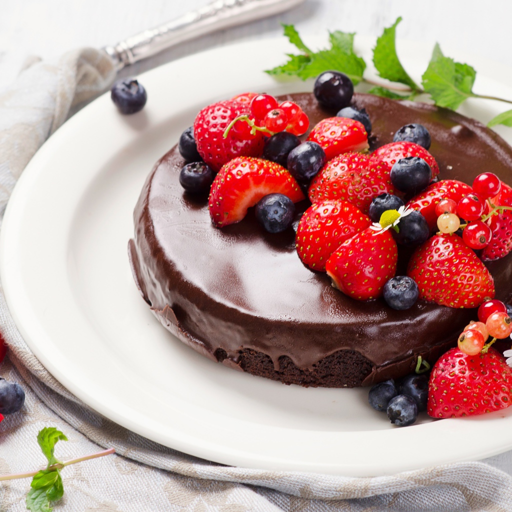 Вкусный торт в шоколаде с ягодами свежей клубники и черники