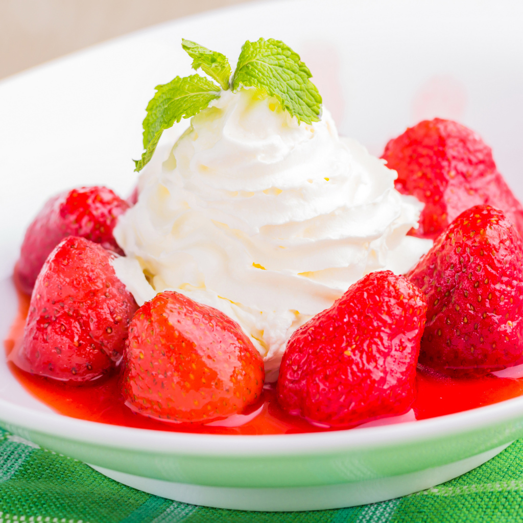 Вкусные сливки с клубникой на белой тарелке