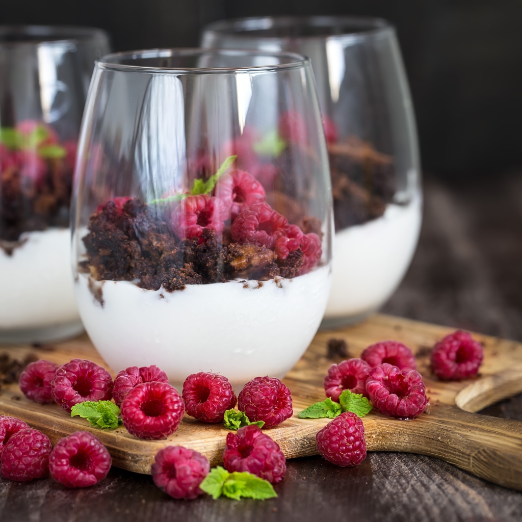 Десерт со сливками, шоколадом и свежей малиной в стеклянных стаканах