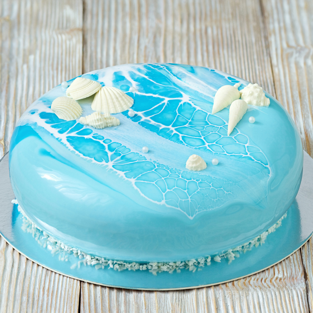 Глянцевый торт голубого цвета украшен сахарными ракушками