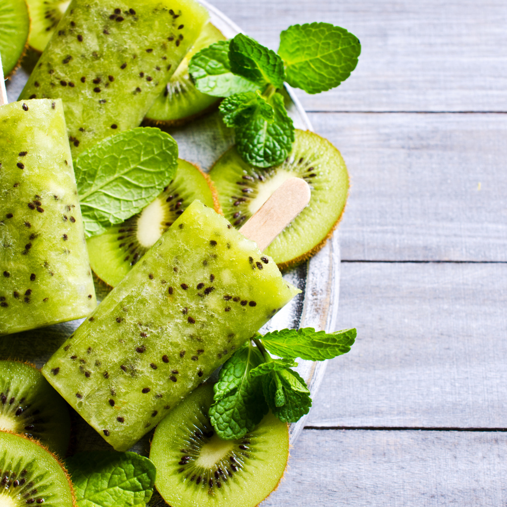 Мороженое с киви и листиками мяты на деревянном столе