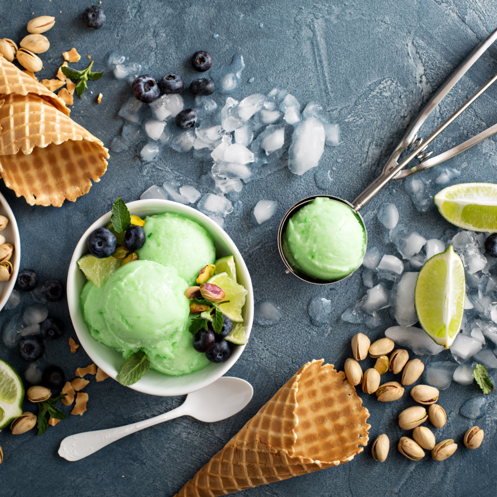 Мороженое с лаймом и фисташками на столе с вафельными рожками и льдом
