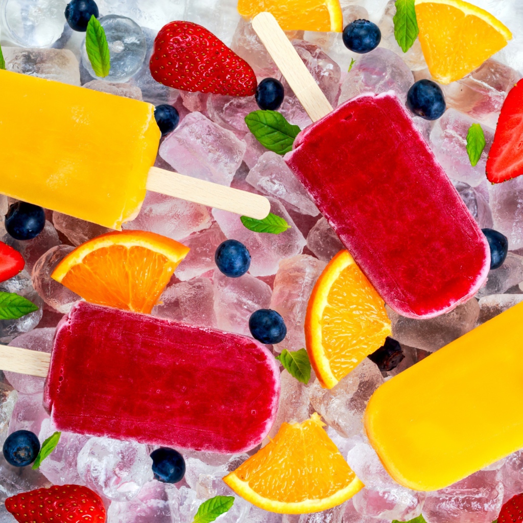 Разноцветное фруктовое мороженое с ягодами лежит на кусочках льда