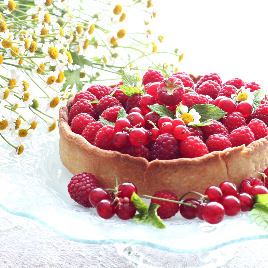 Пирог с ягодами малины и смородины на столе с ромашками