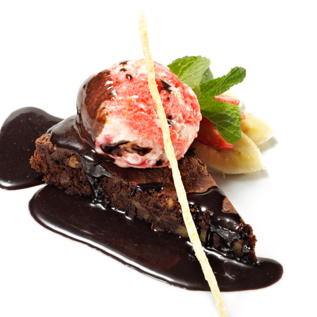 Кусок пирожного с шоколадом и шариком мороженого на белом фоне