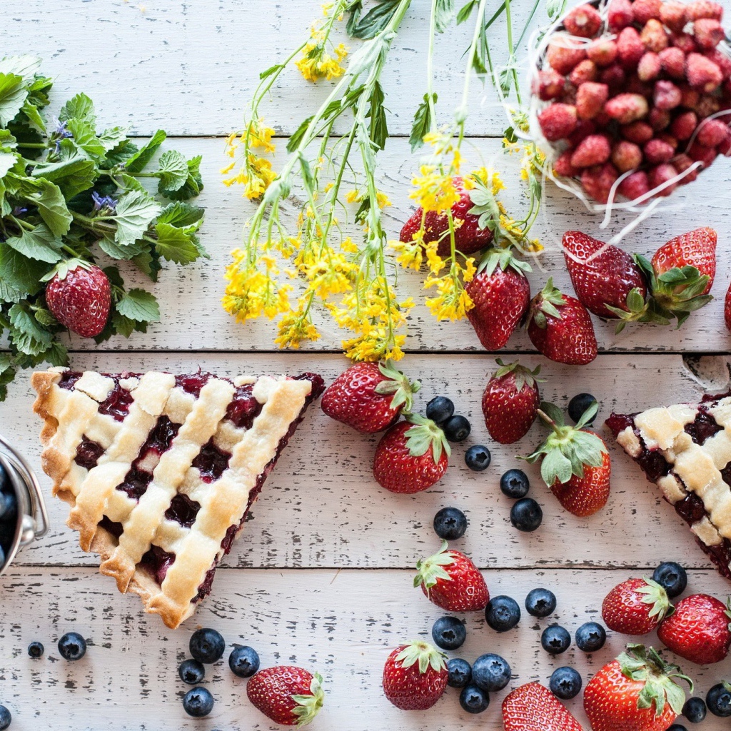 Кусочки пирога на столе с ягодами клубники и черники