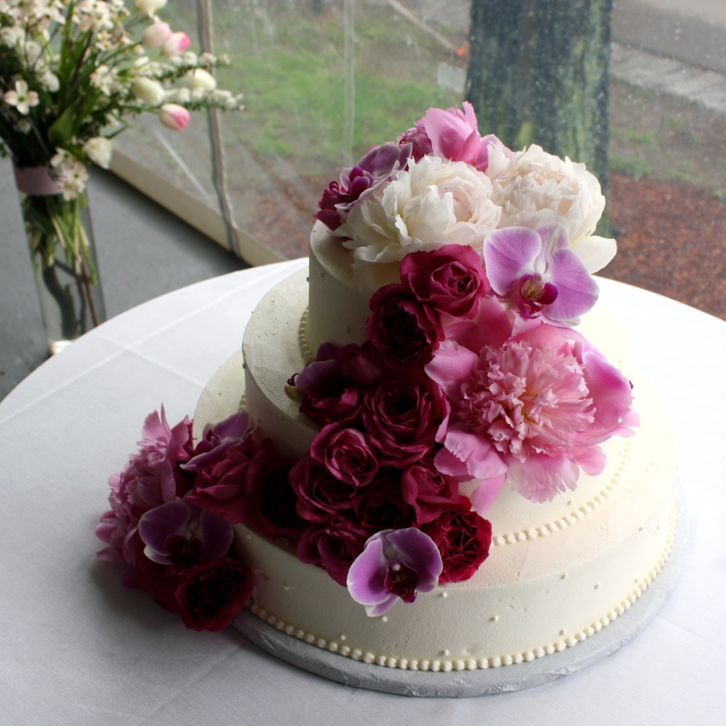 Большой свадебный торт украшен живыми цветами