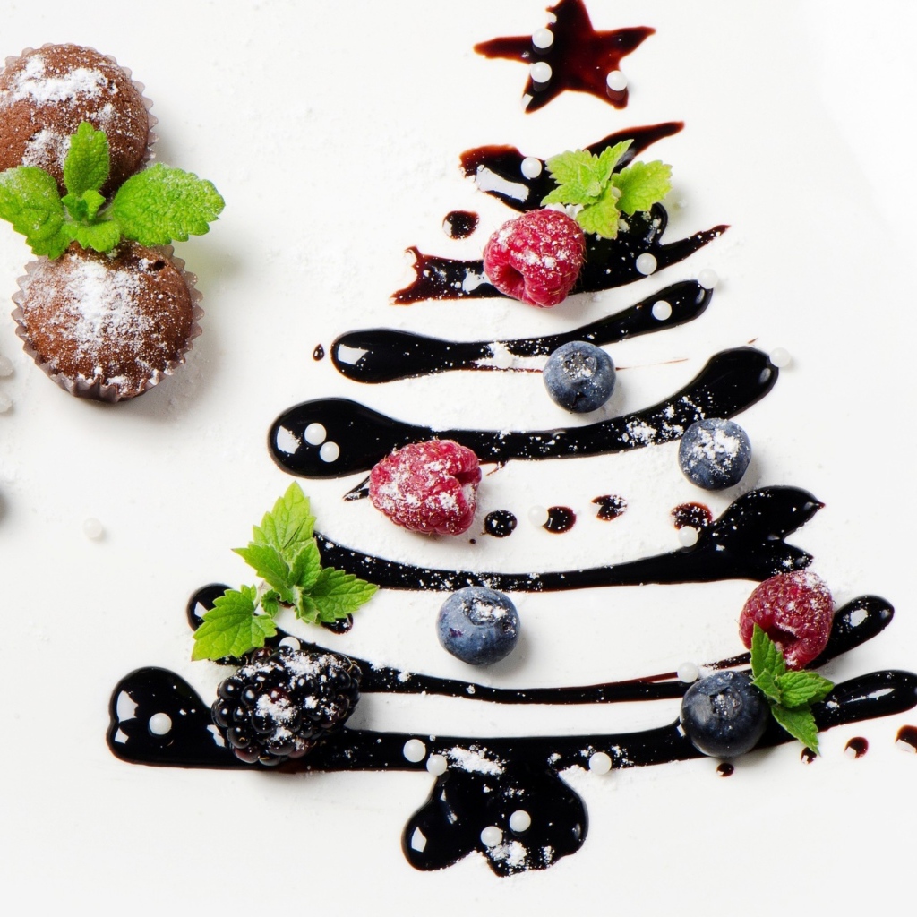 Три кекса и нарисованная шоколадом елка на белой тарелке