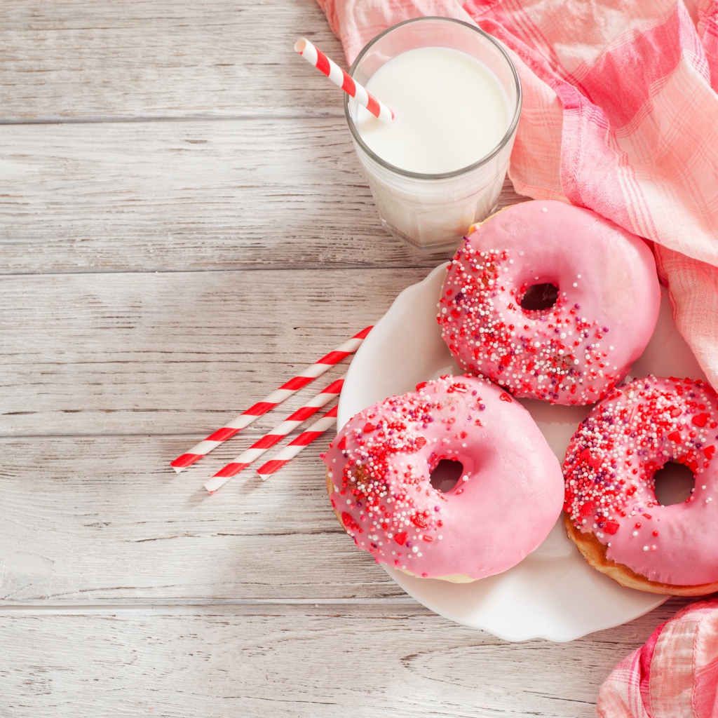 Три аппетитных пончика с розовой сахарной слазурью и стаканом молока