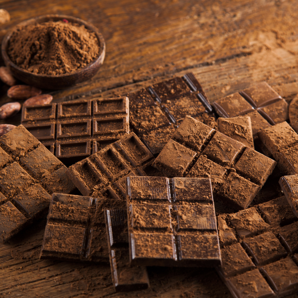 Плитки черного шоколада на столе с какао бобами