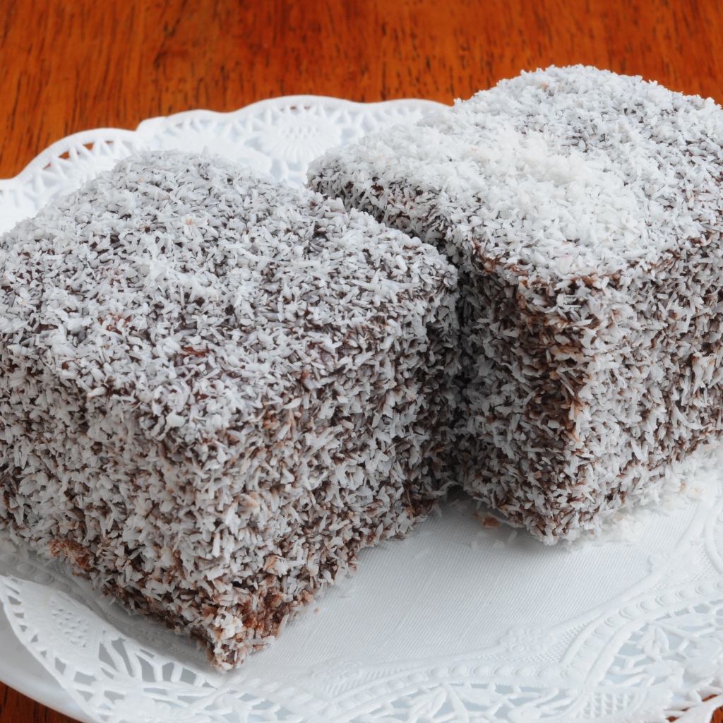 Два кусочка пирожного в кокосовой стружке на белой тарелке