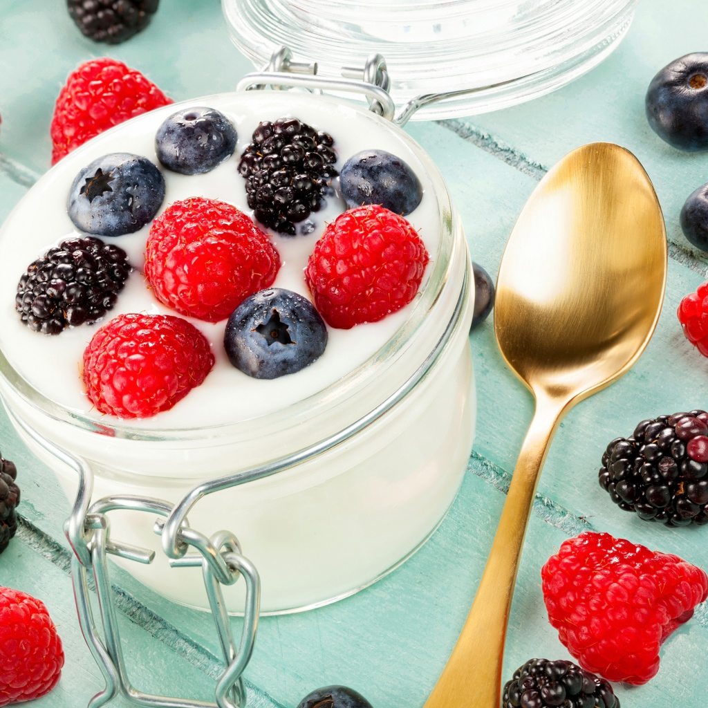 Йогурт со свежими ягодами малины, черники и ежевики в стеклянной банке на завтрак