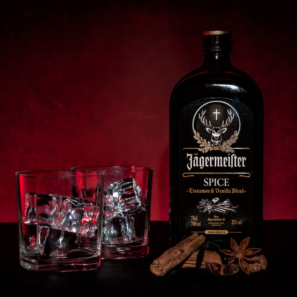 Бутылка ликера Jägermeister на столе с корицей и стаканами
