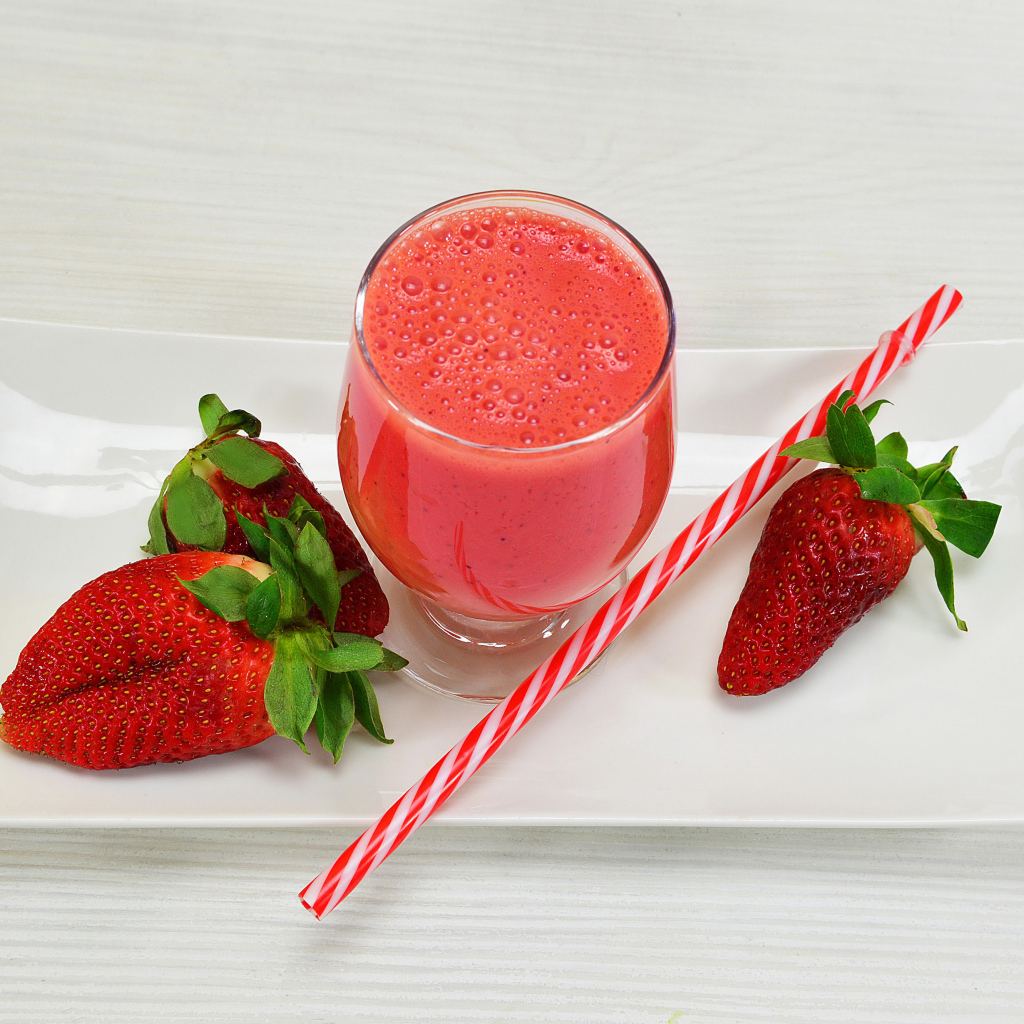 Бокал клубничного коктейля со свежей клубникой и трубочкой