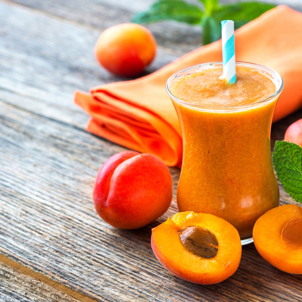 Абрикосовый смузи в стакане на столе со свежими ягодами