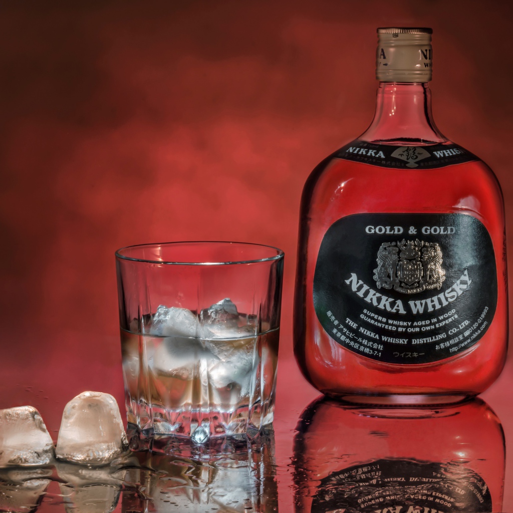 Бутылка Nikka Whisky на столе со стаканом со льдом