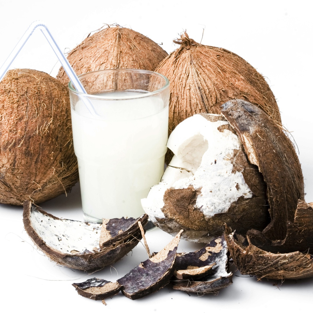Кокосовое молоко в стакане и кокосы на белом фоне