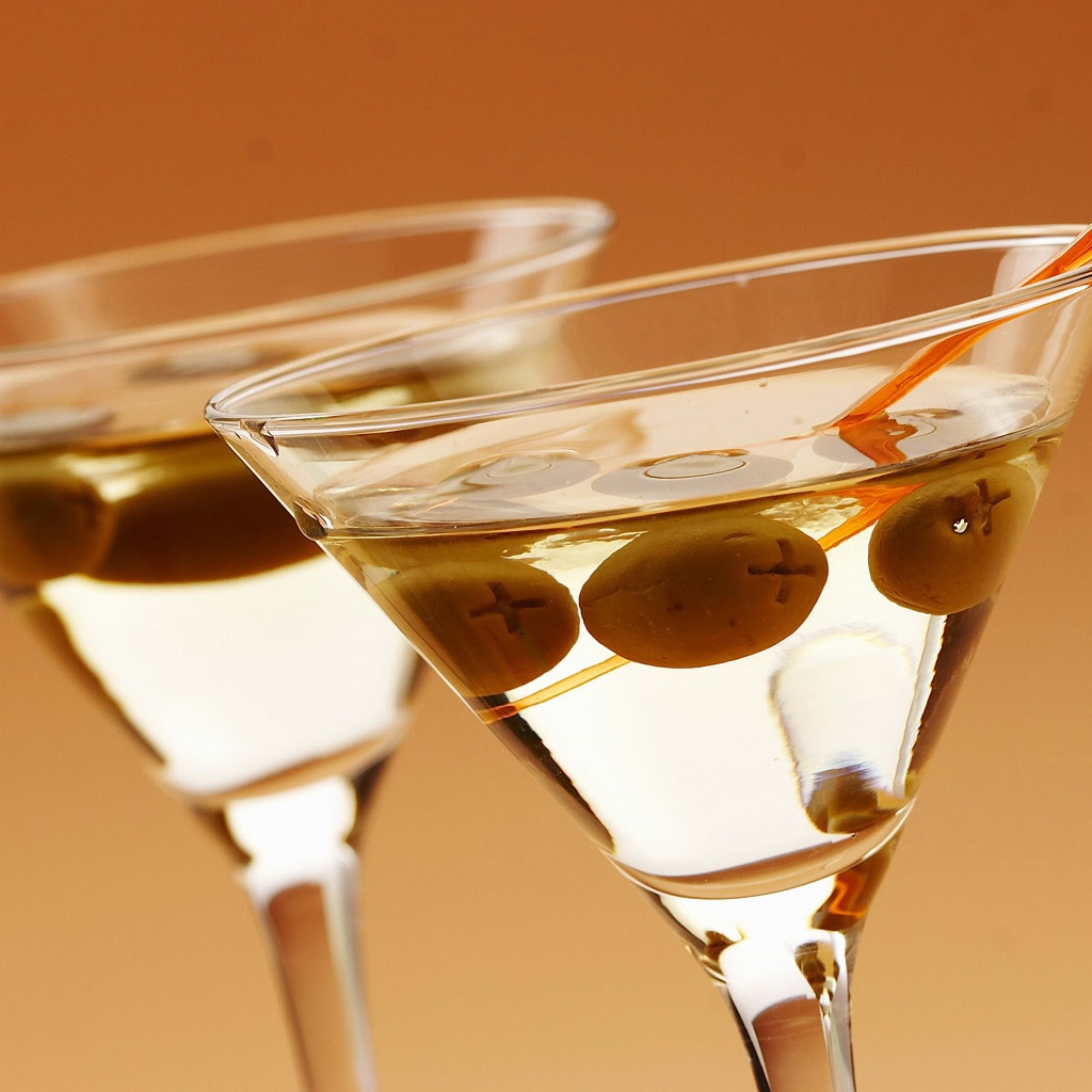 Напиток мартини в бокалах с оливками на кремовом фоне