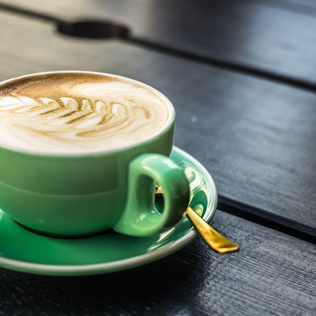 Зеленая чашка капучино с белой пенкой 
