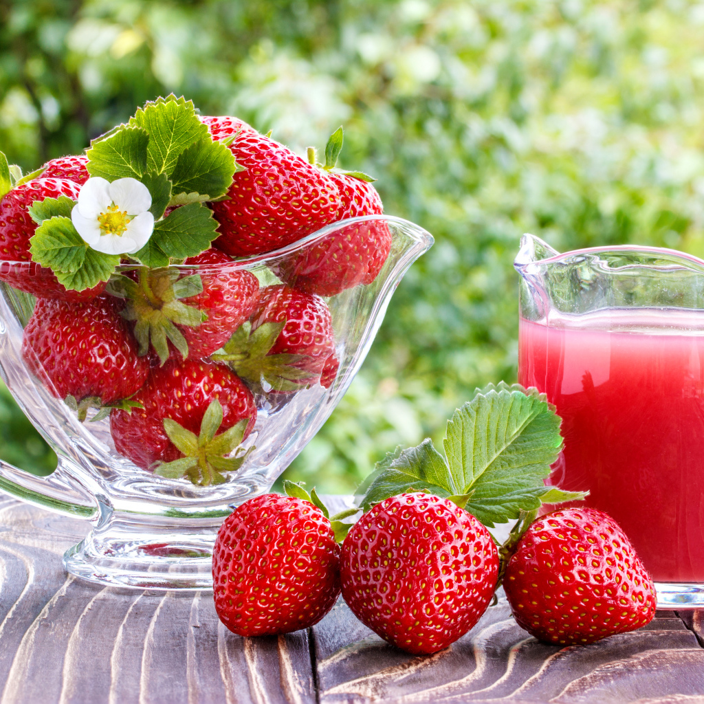 Клубничный сок в стеклянном графине на столе со свежей клубникой