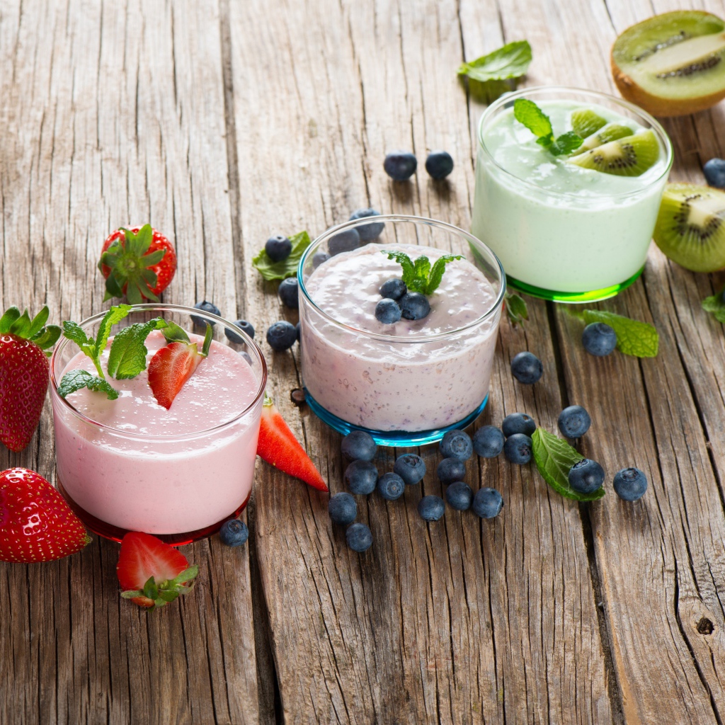 Три стакана смузи с клубникой, киви и черникой и свежими ягодами