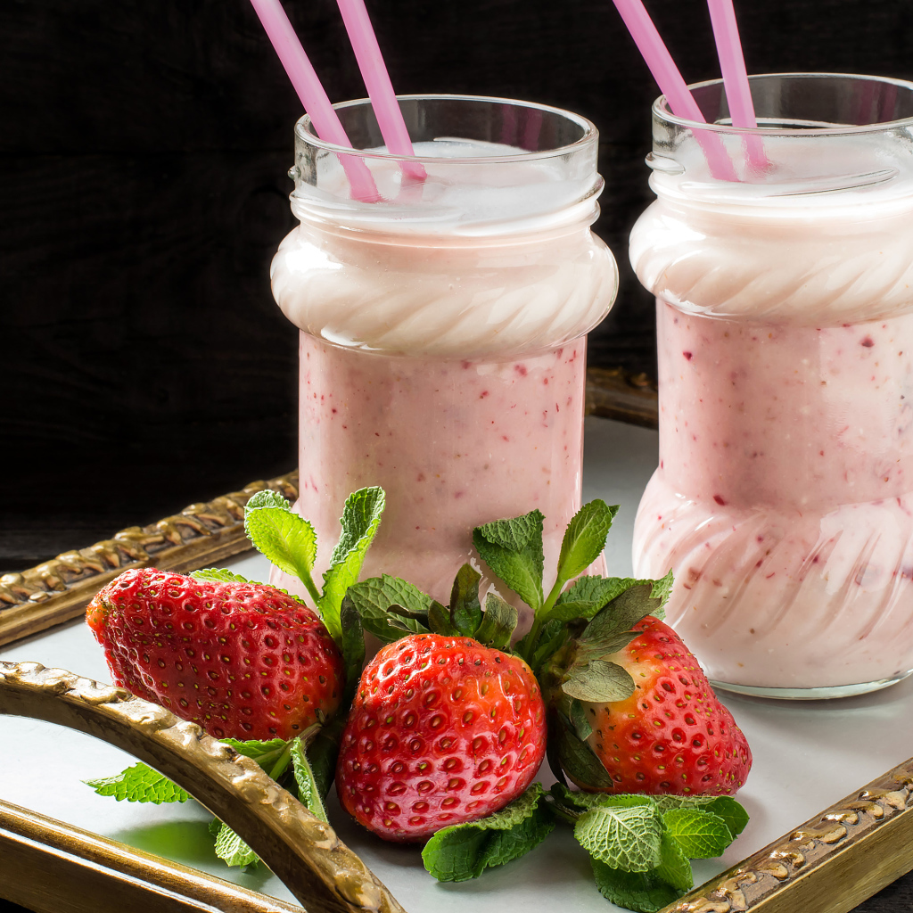 Два свежих клубничных коктейля с трубочками и ягодами клубники