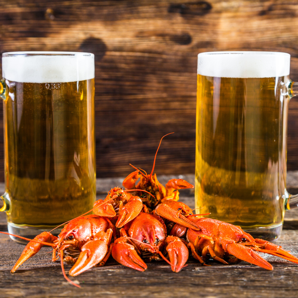 Два бокала пива с красными раками на столе