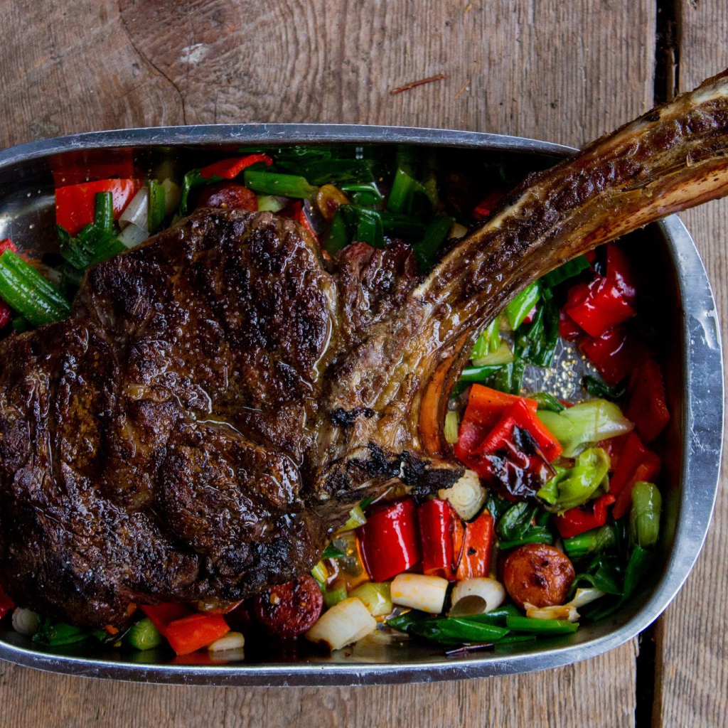 Кусок жареного мяса на ребрышке с овощами