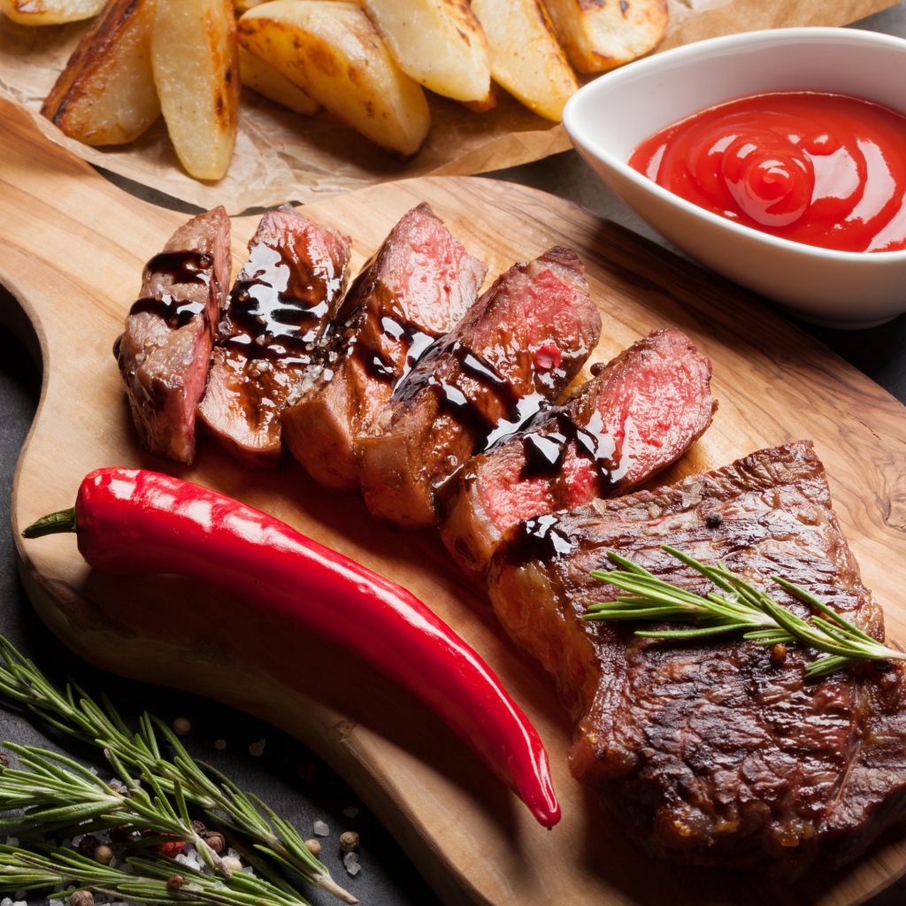 Аппетитный сочный стейк с соусом, красным перцем и специями на столе