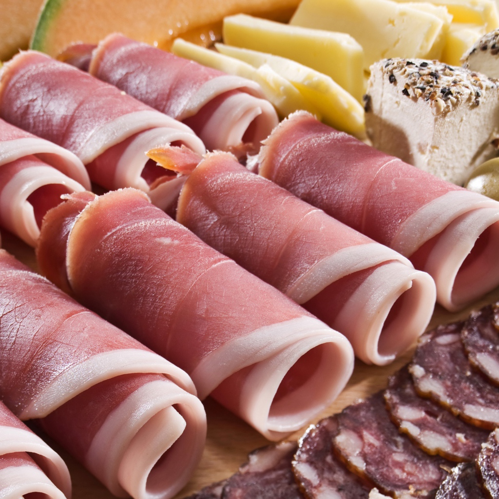 Аппетитные рулетики из бекона на тарелке с зелеными оливками