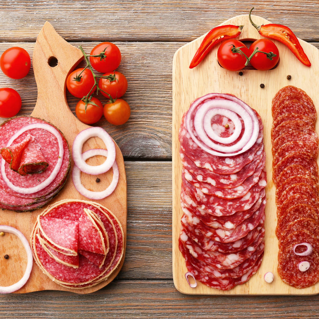Аппетитная колбасная нарезка на разделочной доске с кольцами лука