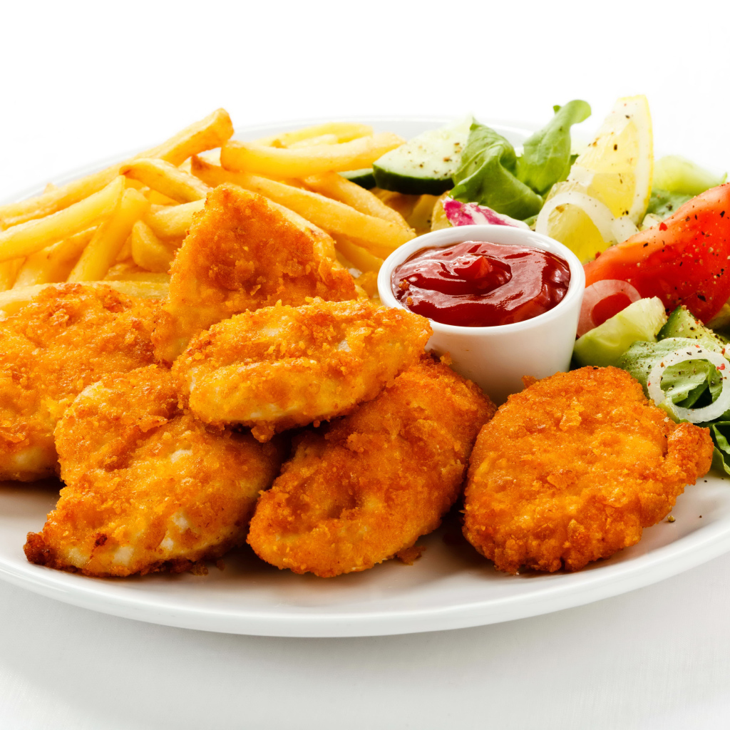 Куриные наггетсы с кетчупом, картофелем фри и салатом на белой тарелке
