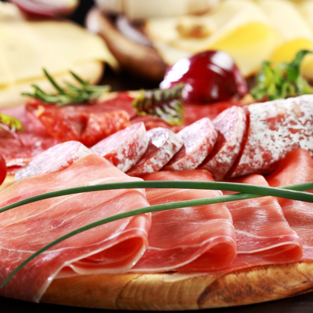 Мясная нарезка на разделочной доске с овощами