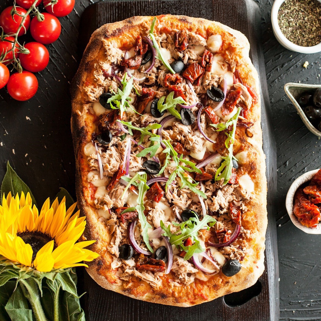 Жареная пицца с мясом на столе с желтым цветком подсолнуха