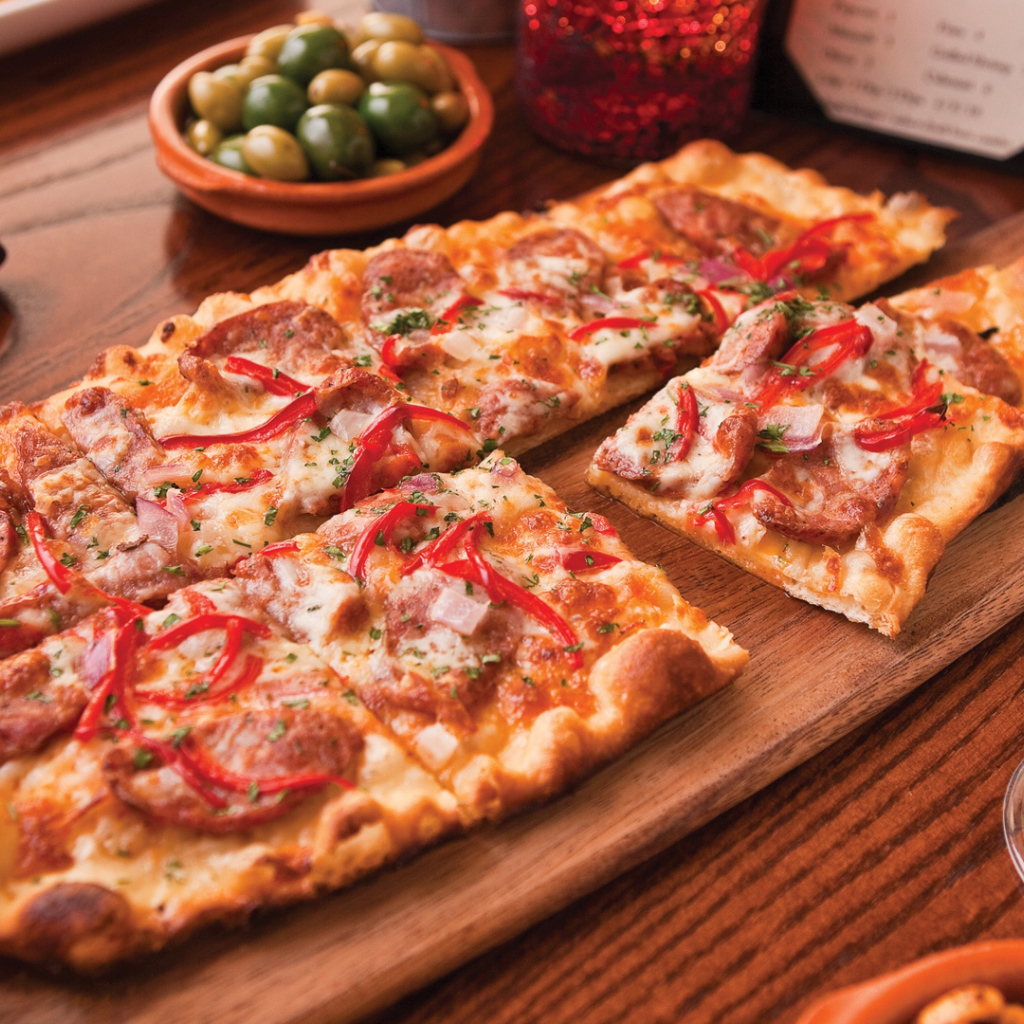 Порезанная на кусочки пицца лежит на разделочной доске