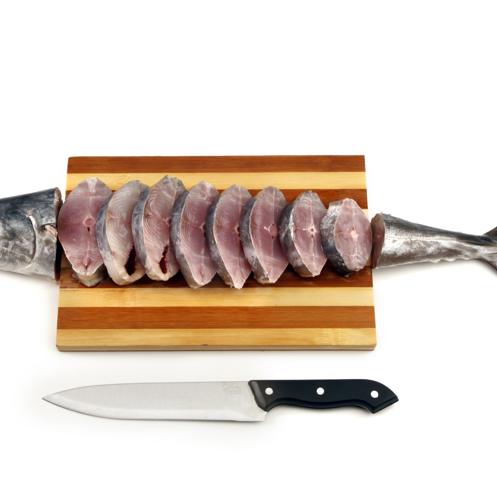 Свежая рыба кусочками на деревянной доске с ножом 