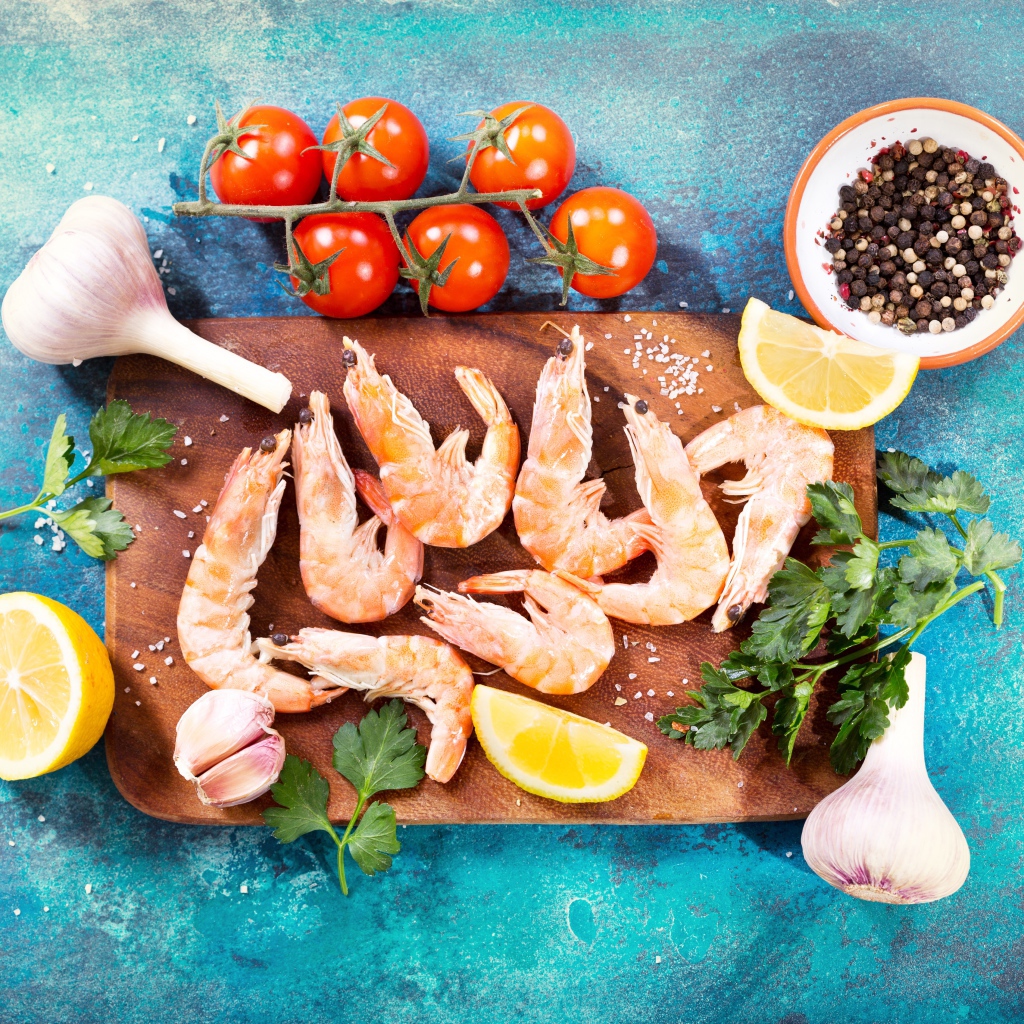 Креветки на разделочной доске с чесноком, лимоном и специями