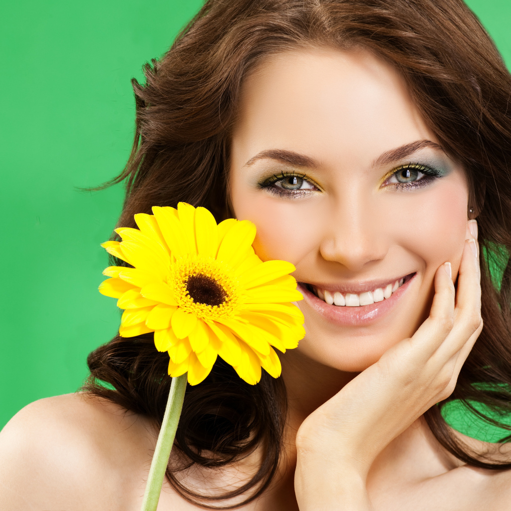 Девушка с красивой улыбкой и цветком желтой герберы в руках