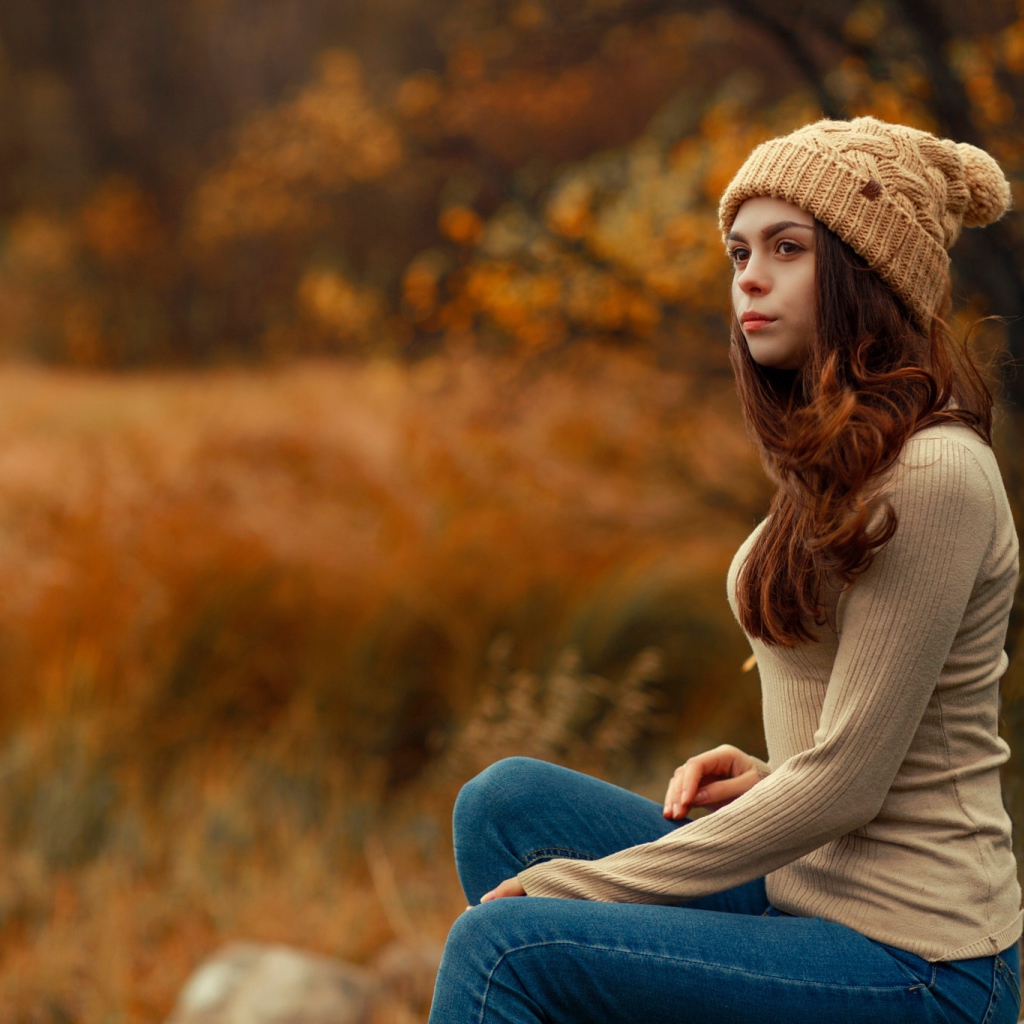 Молодая девушка в синих джинсах и теплой шапке