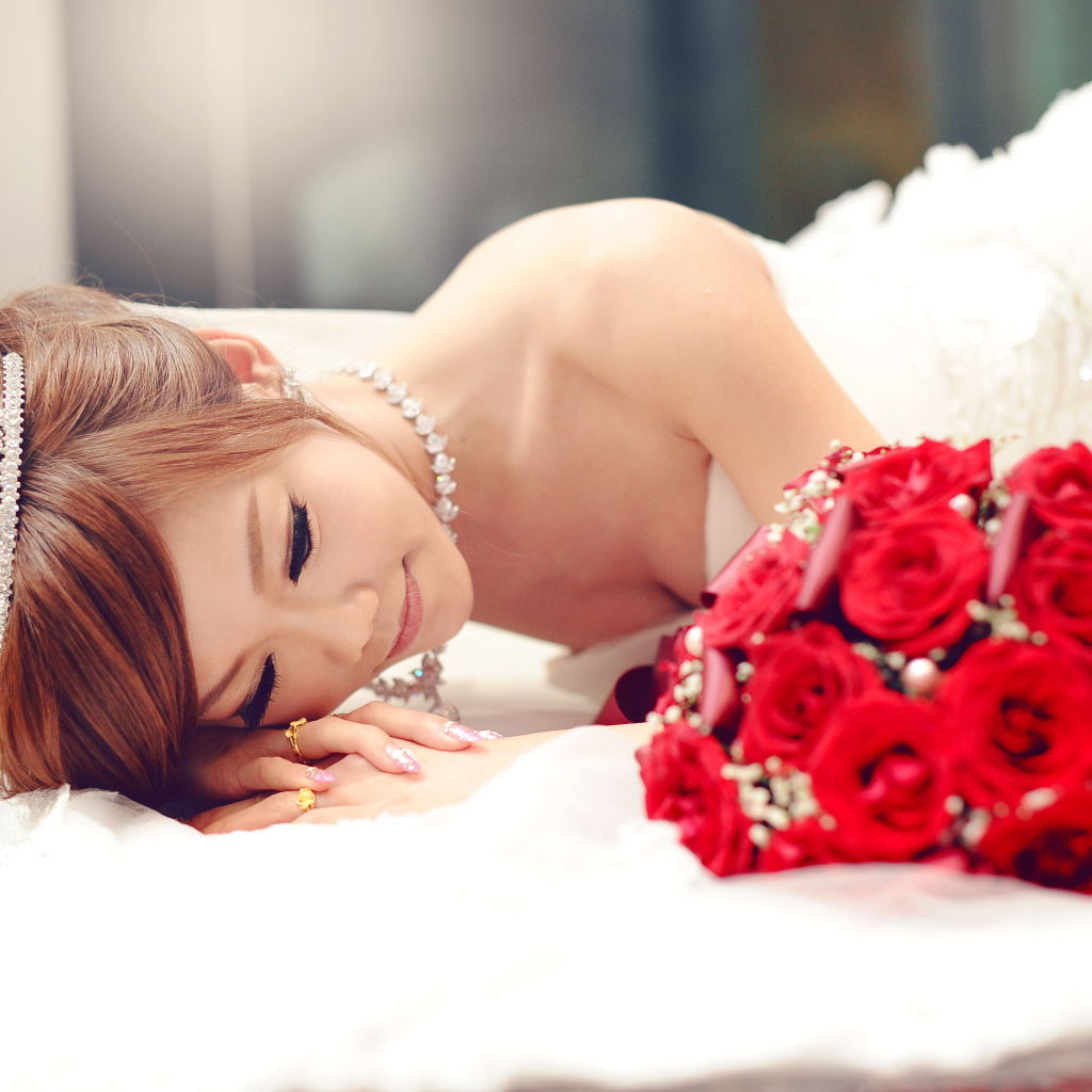 Красивая девушка азиатка в свадебном платье с букетом красных роз