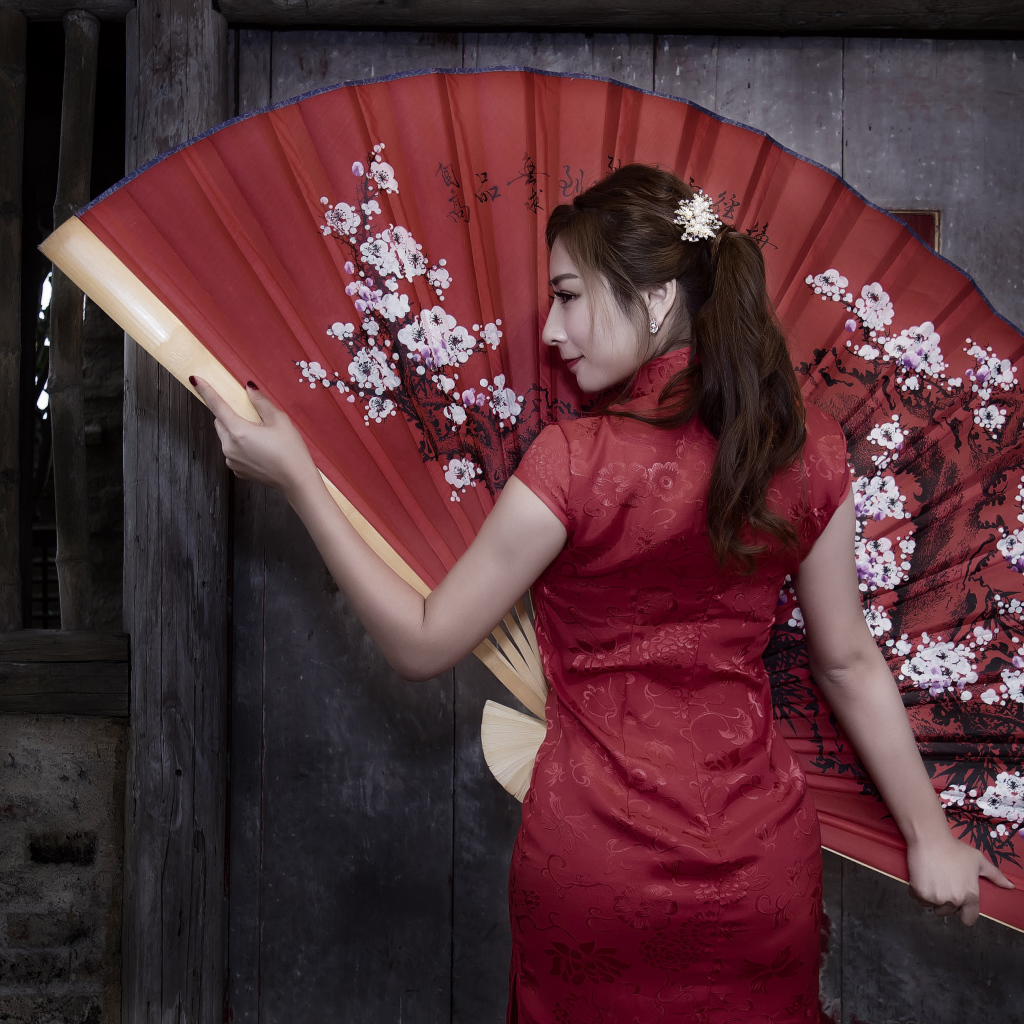Красивая девушка азиатка в красном платье с большим веером